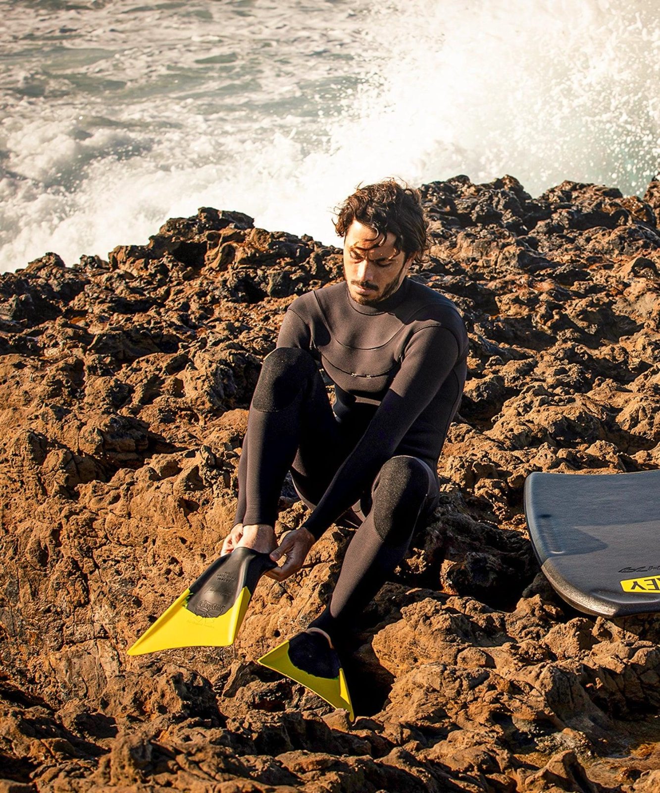 Bodyboarder putting on Churchill Makapuu fins on the rocks