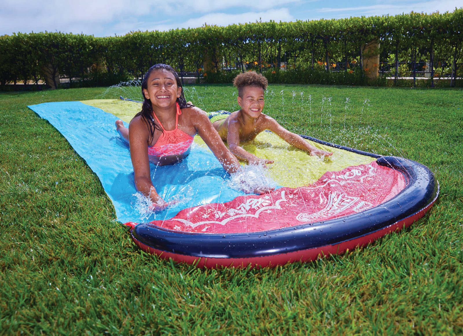 Kids sliding down a Slip ’N Slide on the lawn